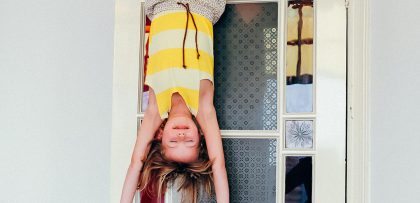 kind hangt ondersteboven aan een deur