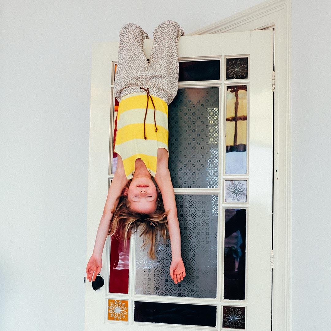 kind hangt ondersteboven aan een deur